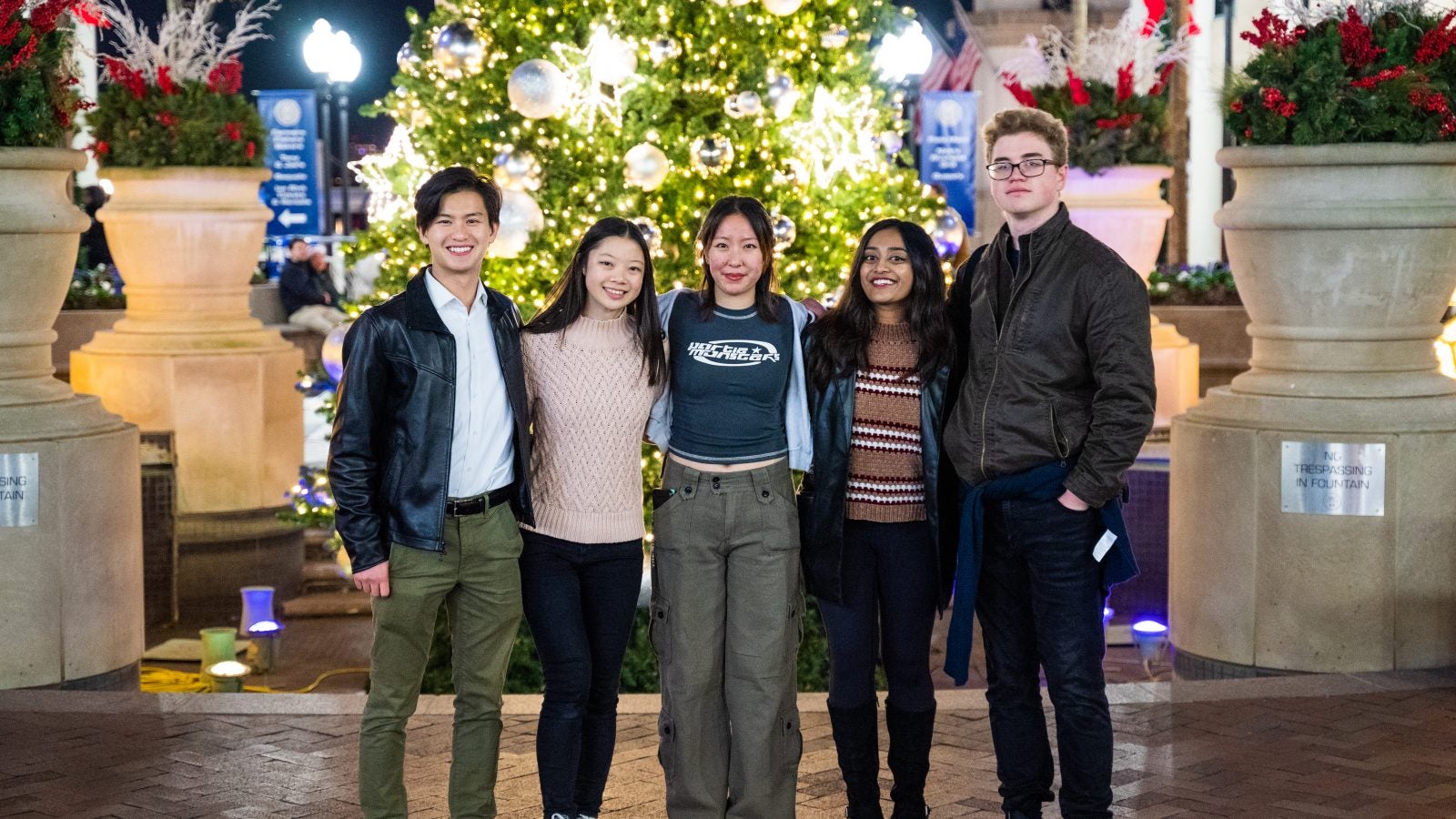 Bennie stands with his friends in front of a Christmas tree