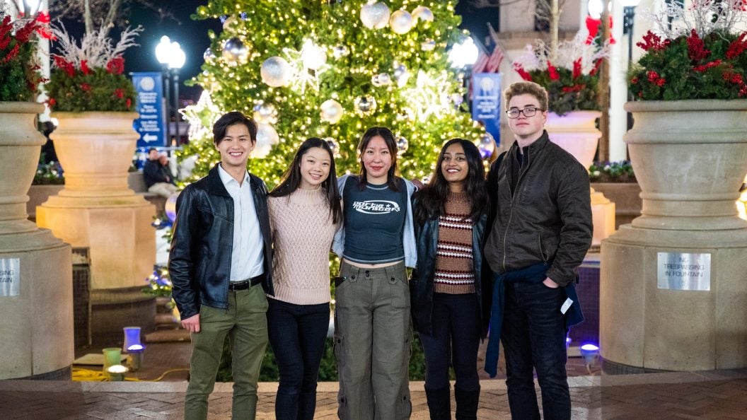 Bennie stands with his friends in front of a Christmas tree