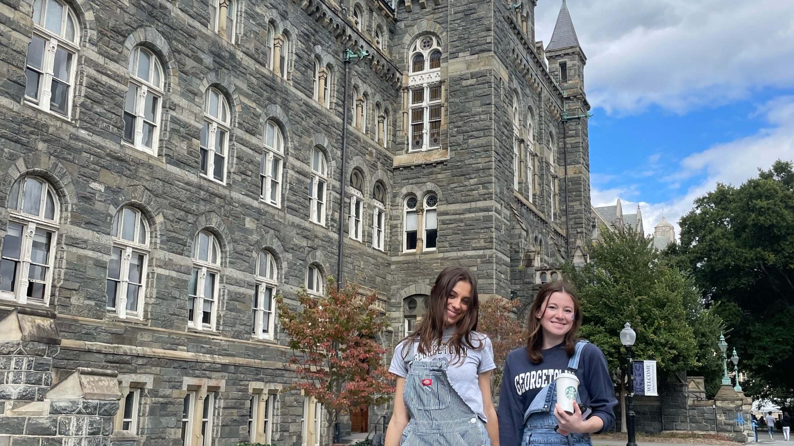 Ava and a friend stroll hand in hand in front of Healy hall while in GA attire