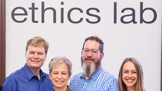 Nitin Vaidya, Ray Essick, Maggie Little, Mark Maloof, Elizabeth Edenberg and Jonathan Healy standing in front of the Ethics Lab sign.